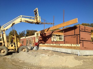 J- UH An engineered beam being lifted into position; steel columns were placed within the floor structure to recieve the steel ridge beam